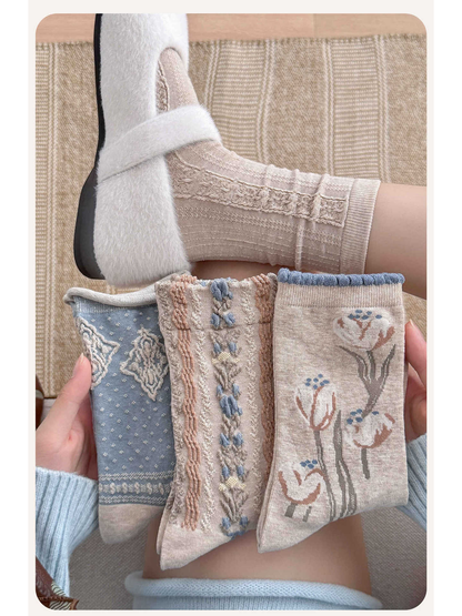 Three patterned crew sock styles held beside a worn openwork pair