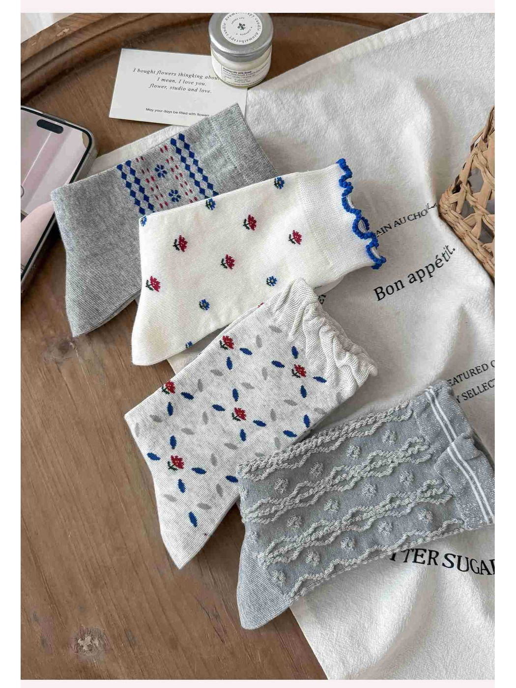 Four gray and ivory patterned crew sock styles arranged on a wooden table