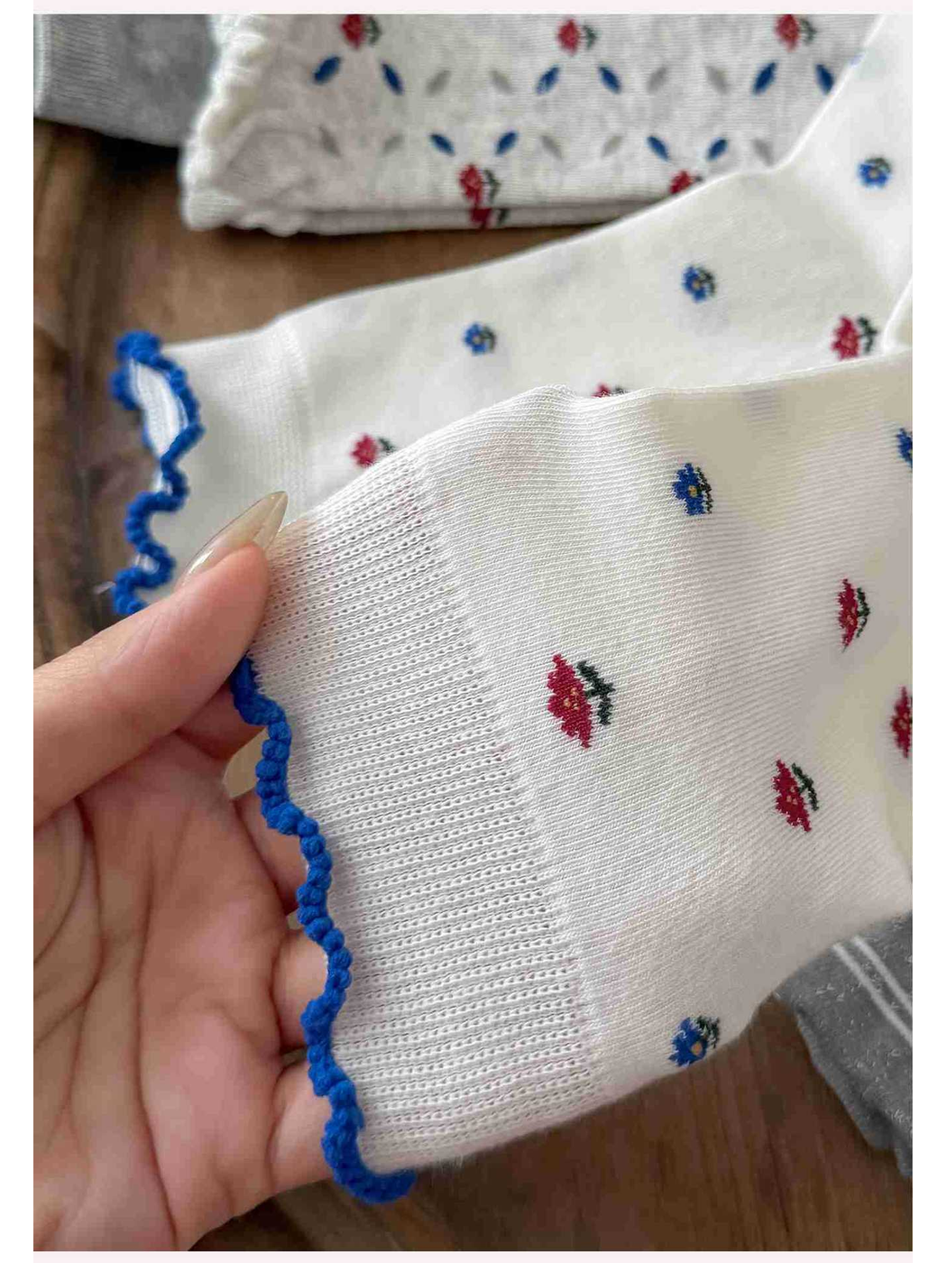 Close-up of an ivory floral sock with a blue scalloped cuff