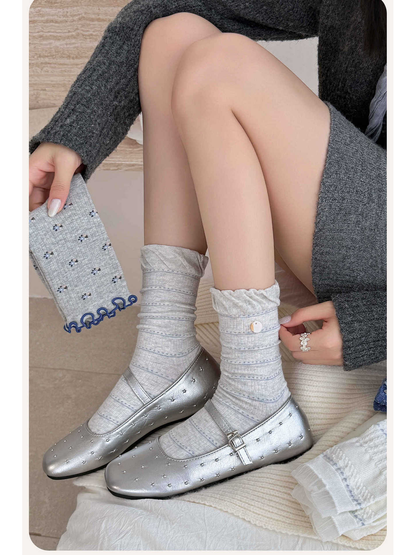 Light gray striped crew socks worn with silver flats