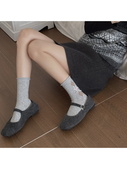Light gray argyle crew socks worn with charcoal Mary Jane shoes
