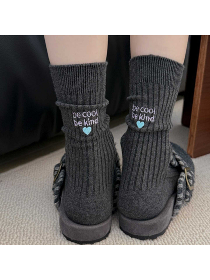 Dark gray embroidered crew socks worn with textured shoes, rear view