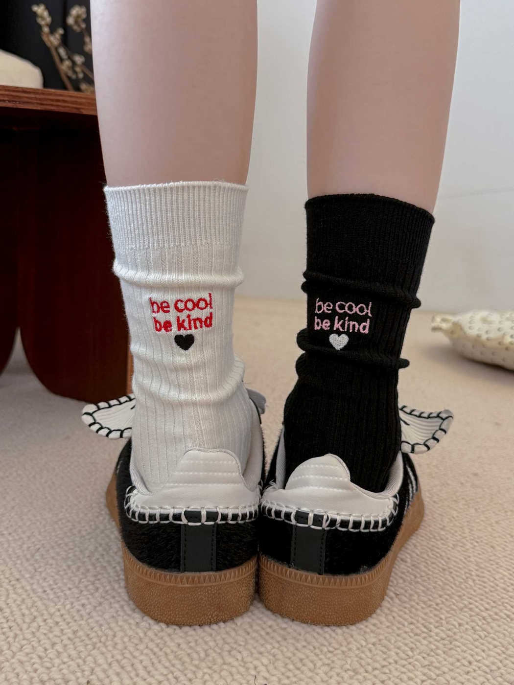 White and black embroidered crew socks worn with black sneakers
