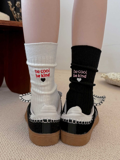 White and black embroidered crew socks worn with black sneakers