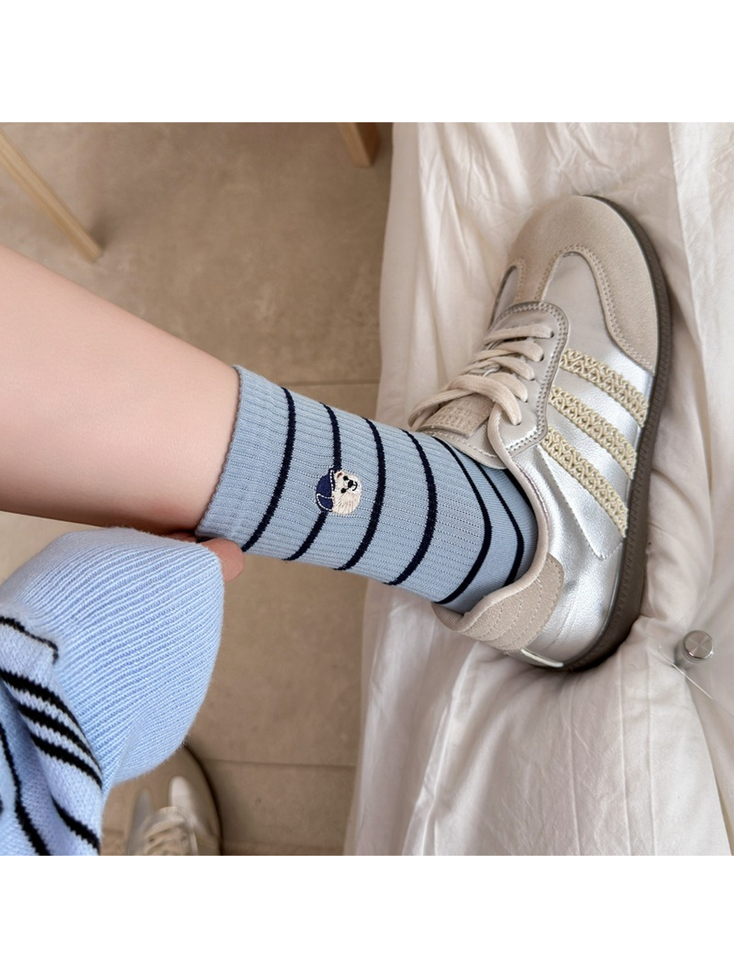 Light blue striped crew sock worn with a silver-tone sneaker