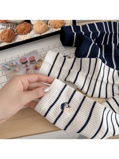 Close-up of ribbed cuffs, narrow stripes and embroidered dog motifs