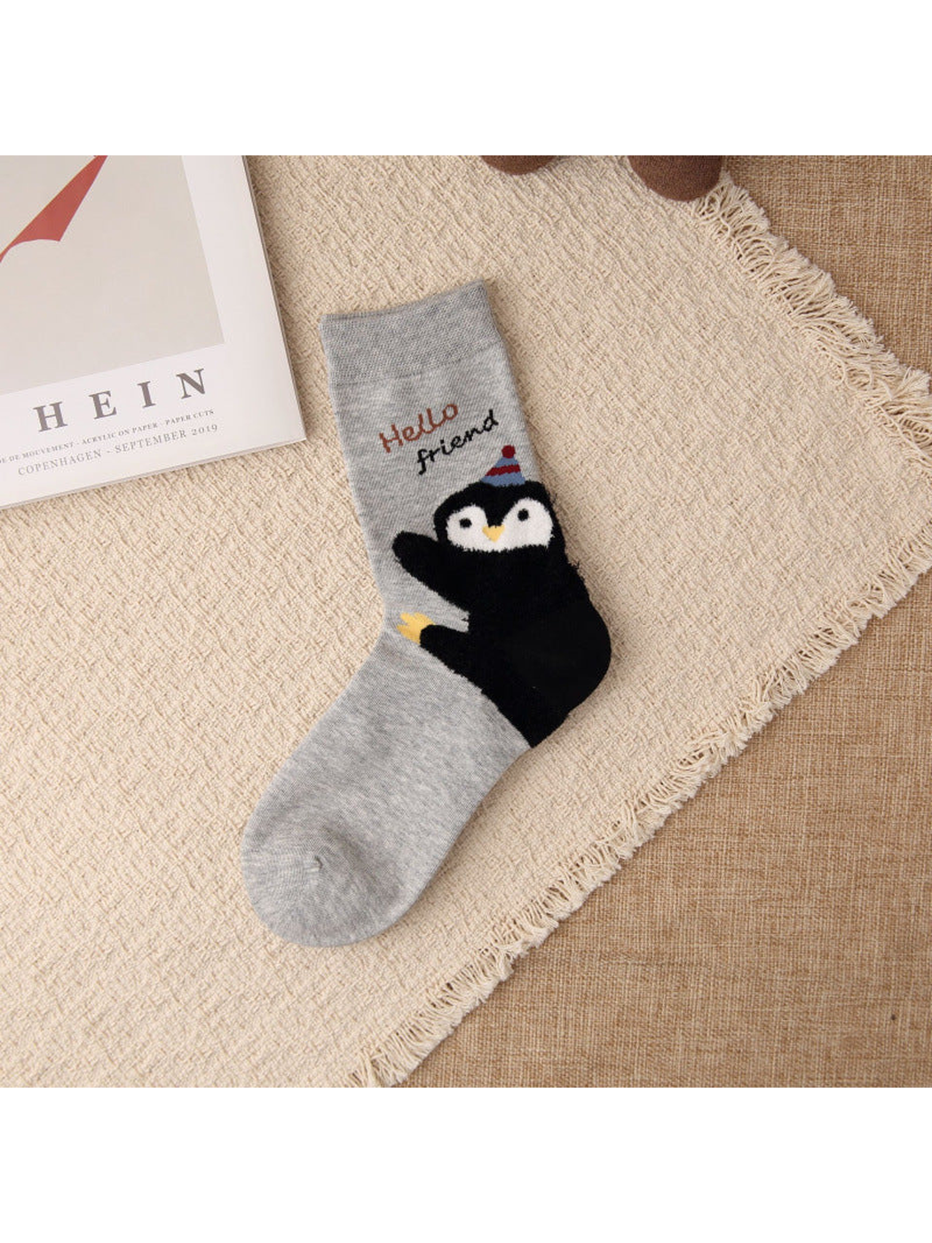 Light gray crew sock with waving penguin motif