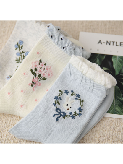 Close-up of layered ruffled cuffs with bouquet and rabbit wreath motifs