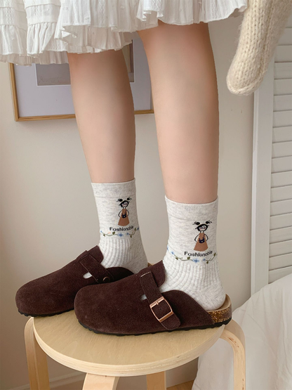 Light gray cartoon crew socks worn with brown clogs