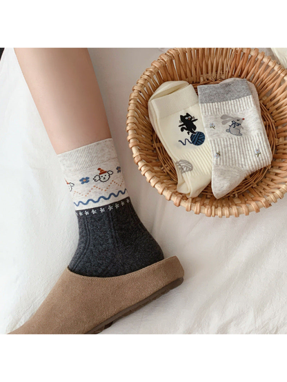 Dark gray animal-motif crew sock worn with a slipper beside two folded designs