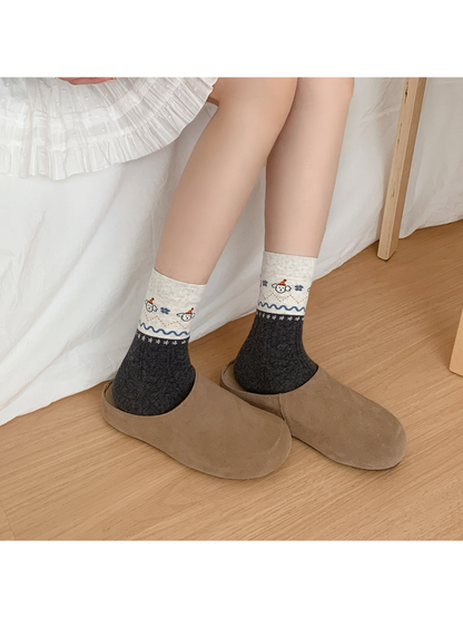 Dark gray patterned crew socks worn with taupe slippers