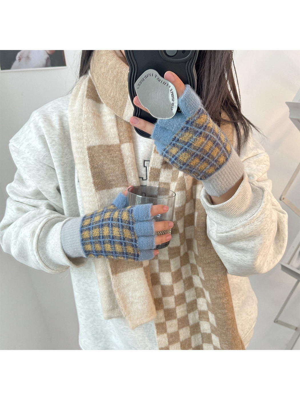 Blue and yellow plaid fingerless gloves worn while holding a glass