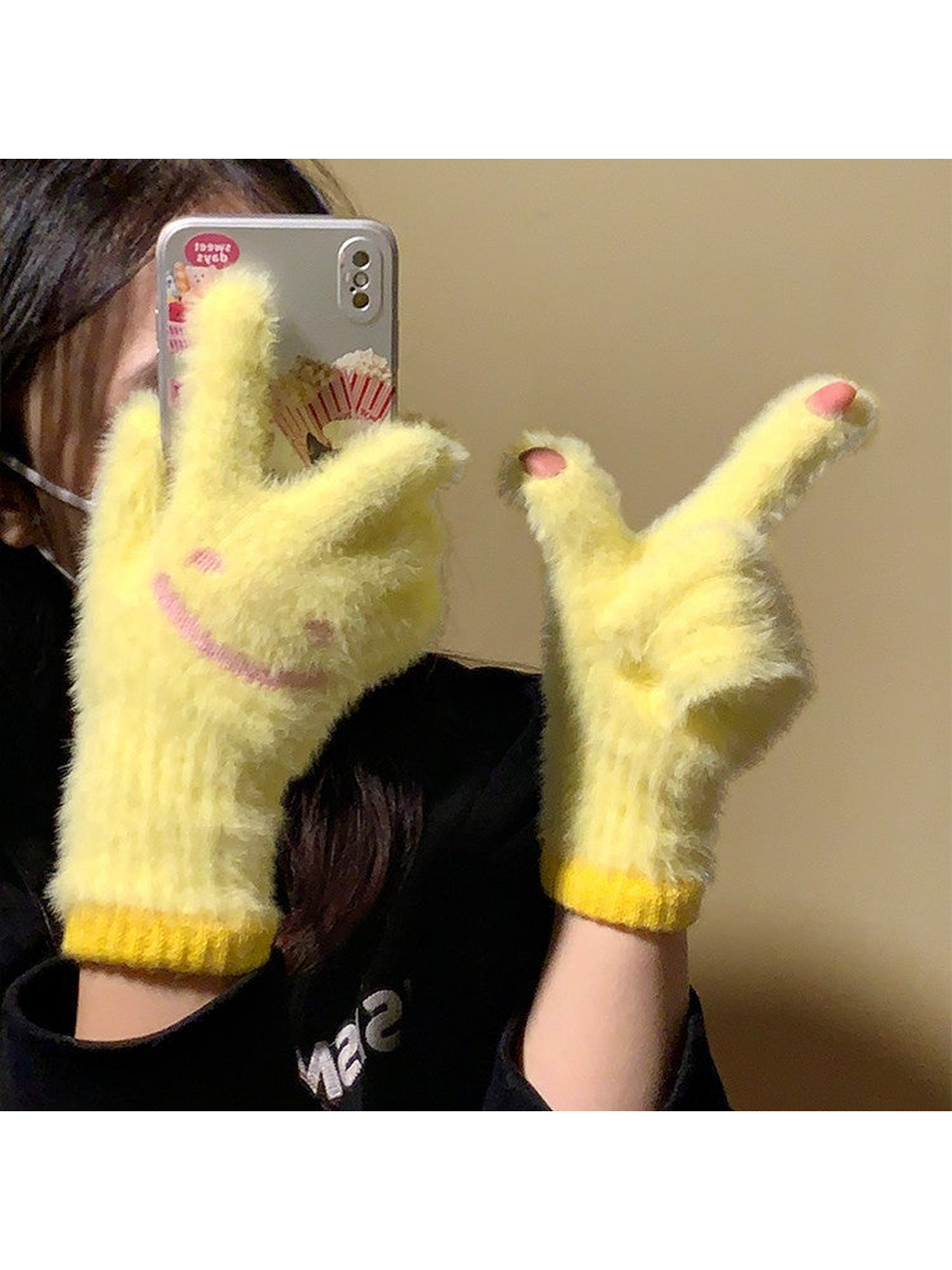 Yellow fuzzy smiley-face gloves worn with raised fingertips