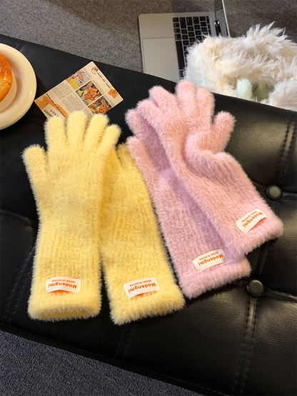 Yellow and pink fuzzy gloves displayed on a dark seat