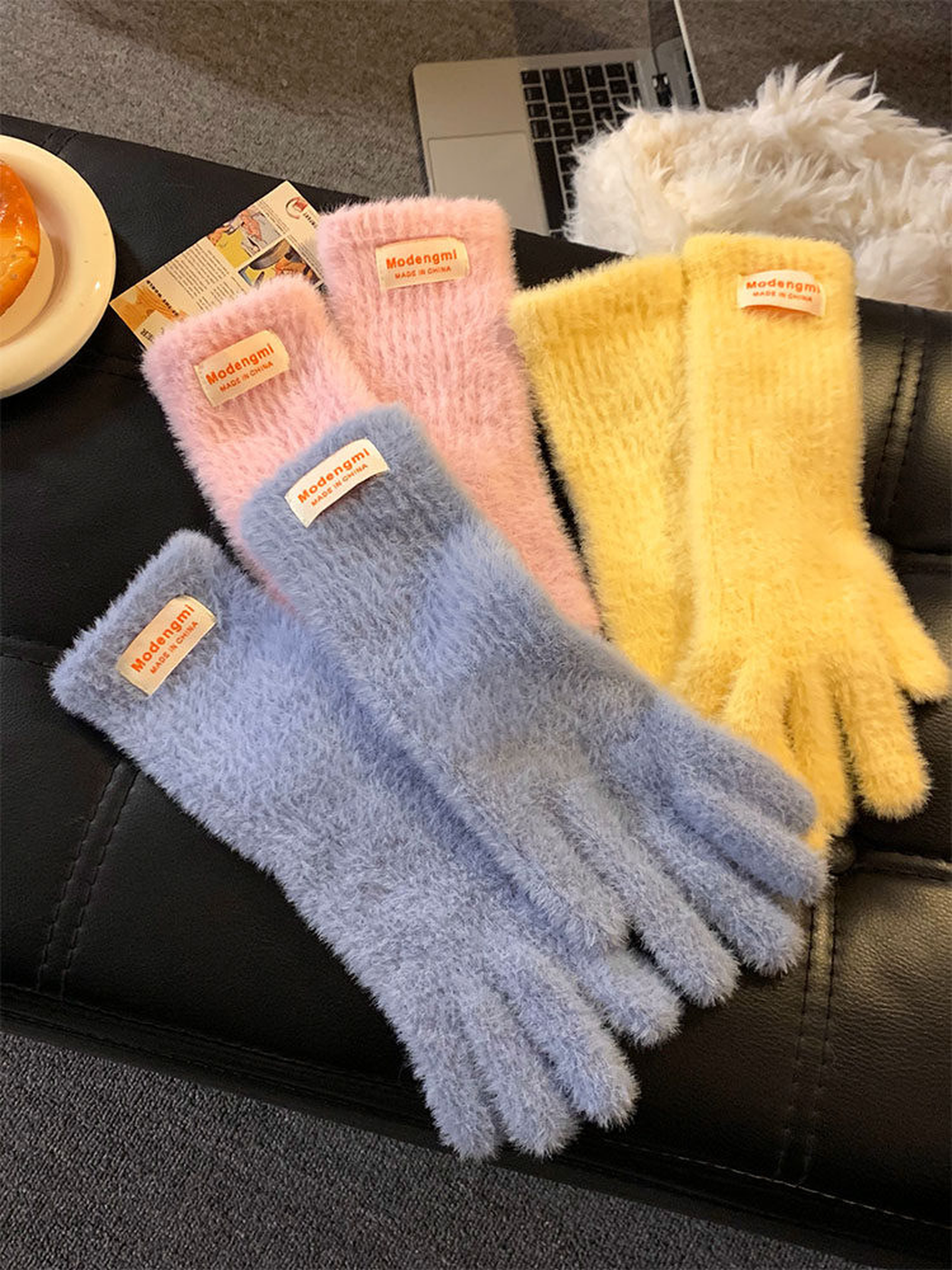 Light blue, pink and yellow fuzzy gloves arranged on a dark seat