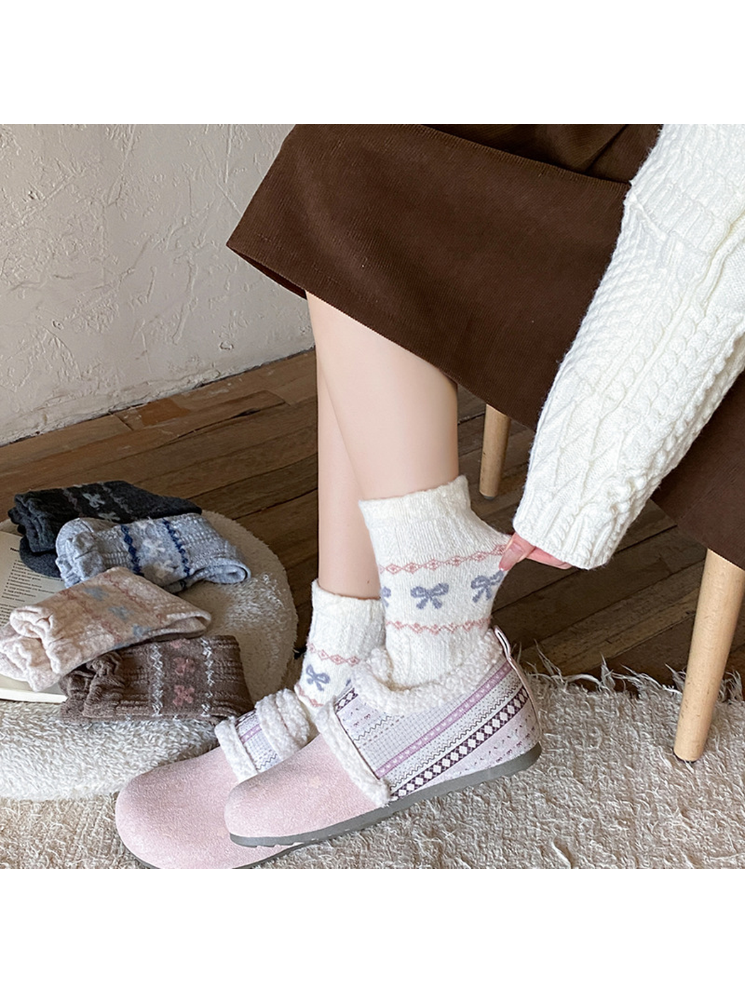 Ivory bow-pattern crew socks styled with pink fleece-lined slippers