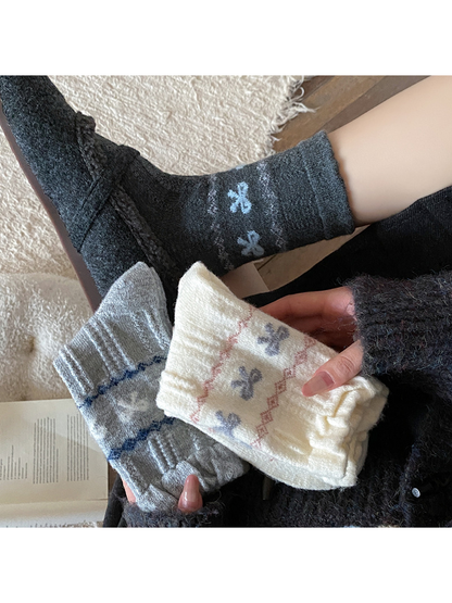 Dark gray bow-pattern socks worn while light gray and ivory styles are held nearby