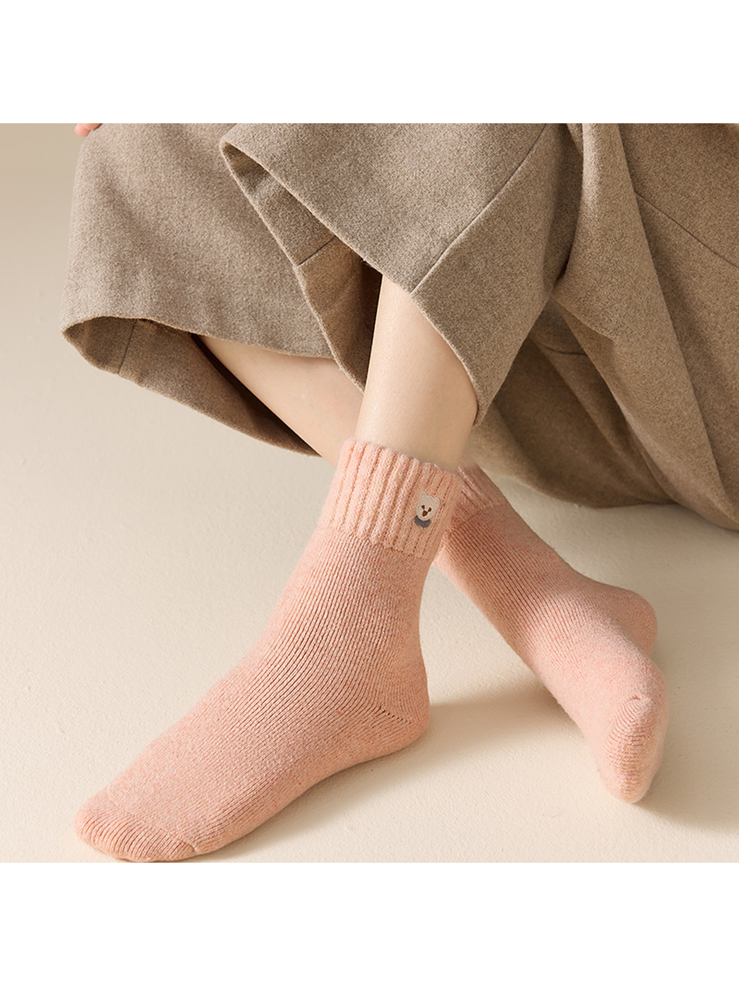 Blush pink ribbed crew socks worn in a seated crossed-leg view