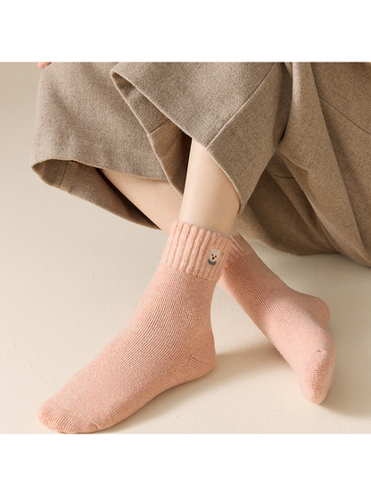 Blush pink ribbed crew socks worn in a seated crossed-leg view