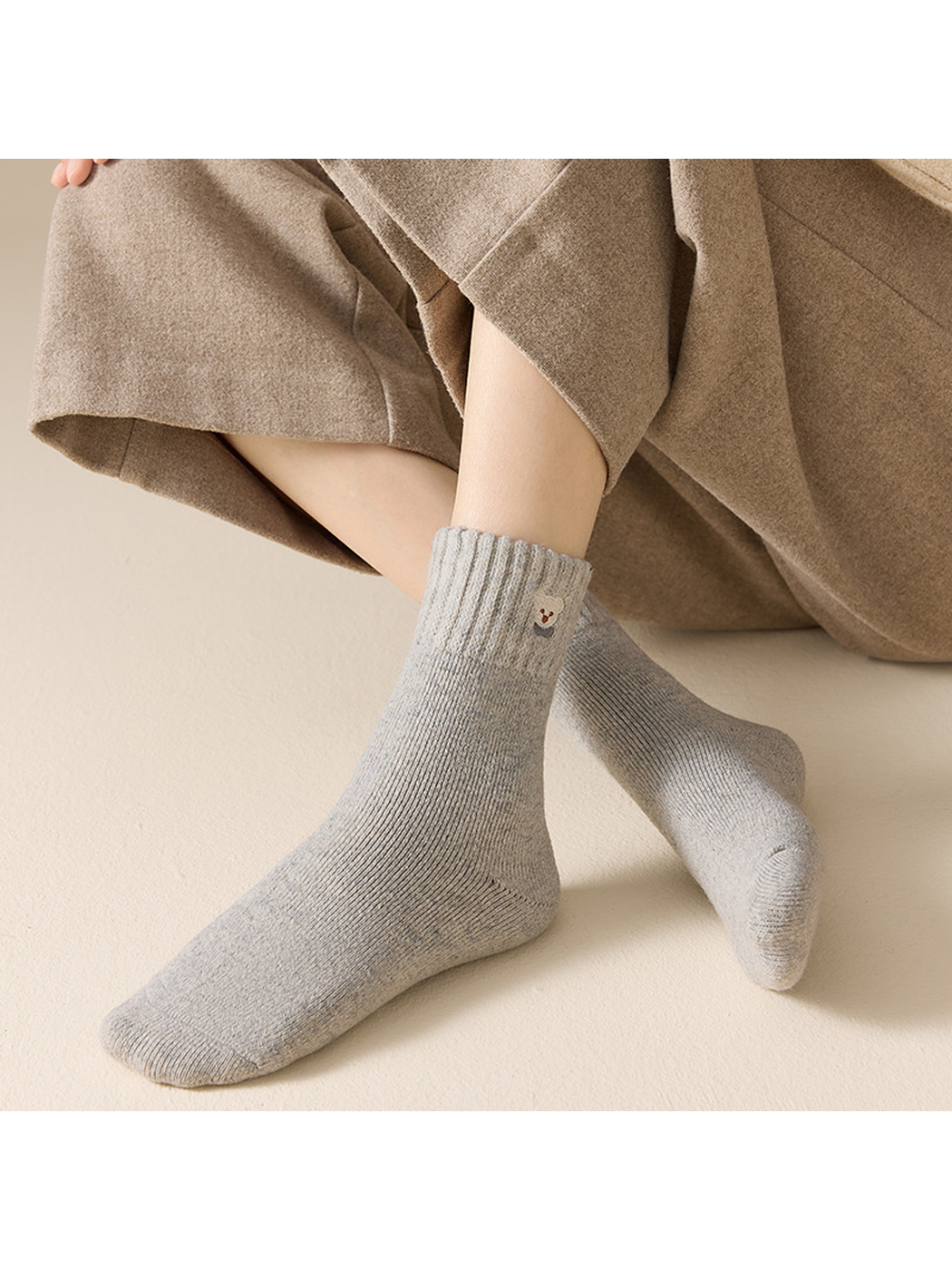 Light gray ribbed crew socks worn in a seated crossed-leg view