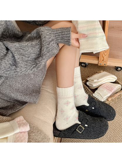 Cross-star crew socks styled with dark clogs while a striped style is held nearby