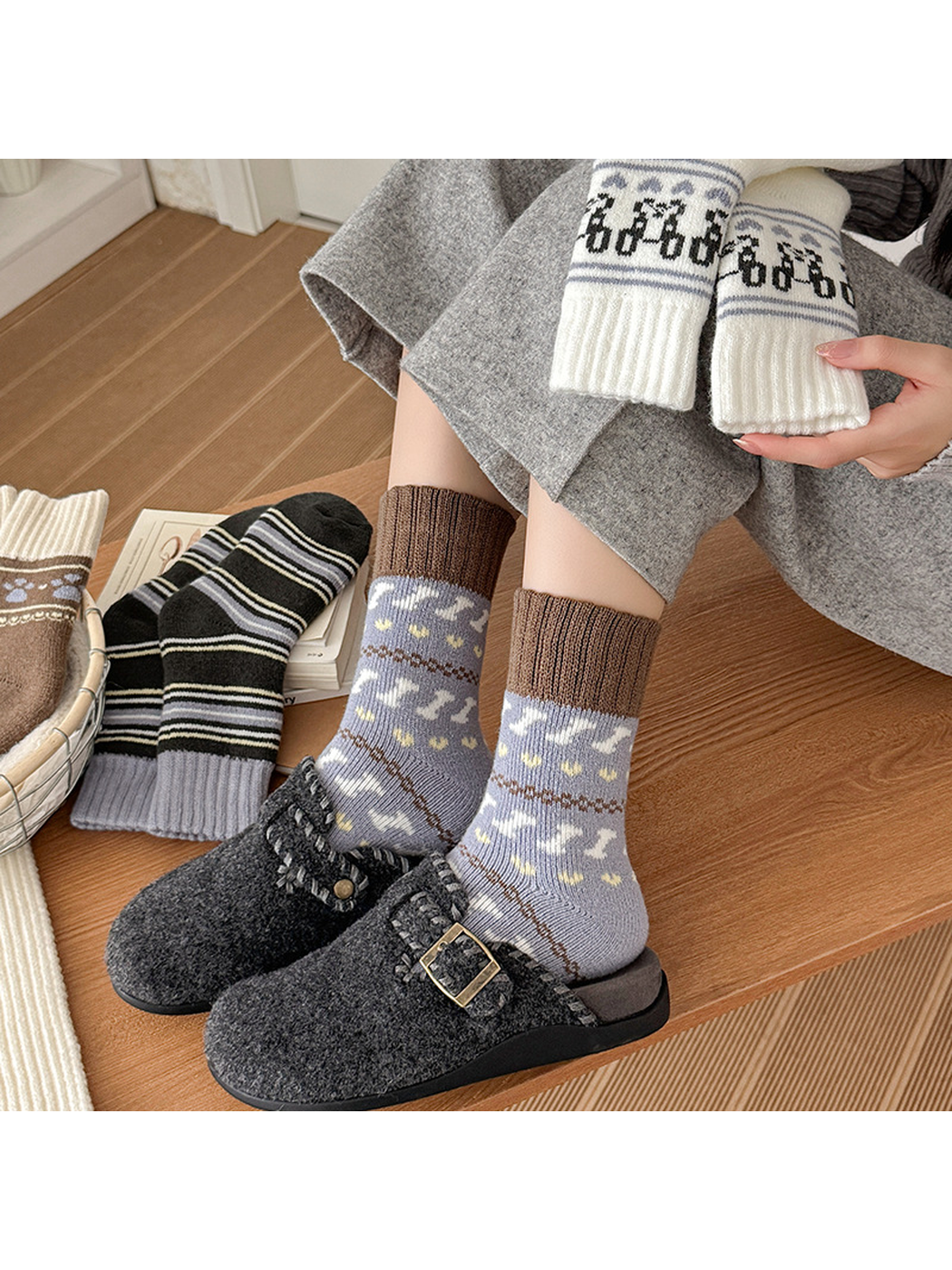 Gray-blue motif socks worn with dark slippers and other sock styles arranged nearby