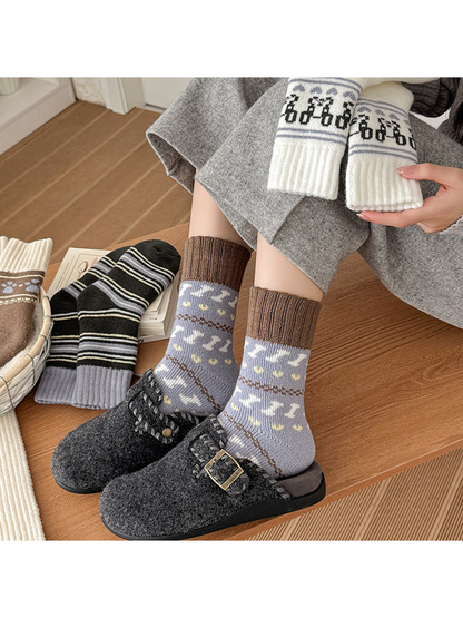 Gray-blue motif socks worn with dark slippers and other sock styles arranged nearby