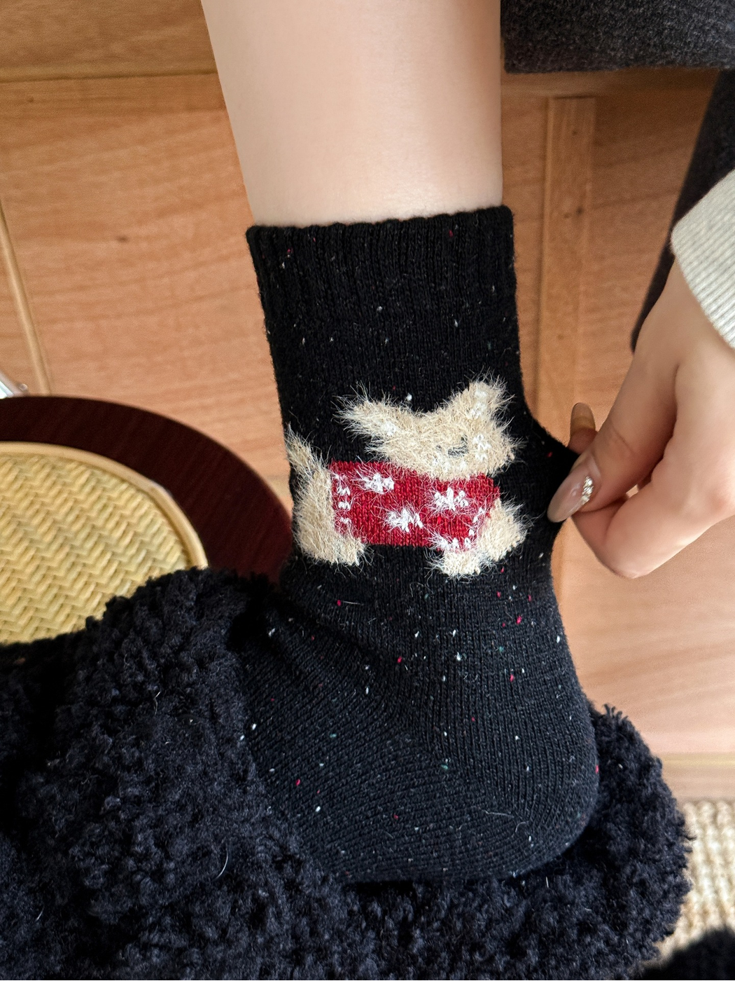Close-up of the red fuzzy cat motif on a black crew sock