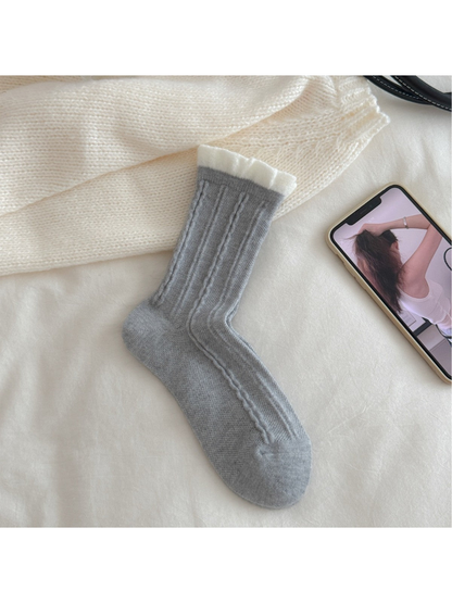 Light gray cable-knit crew sock with contrasting white ruffled cuff, flat view