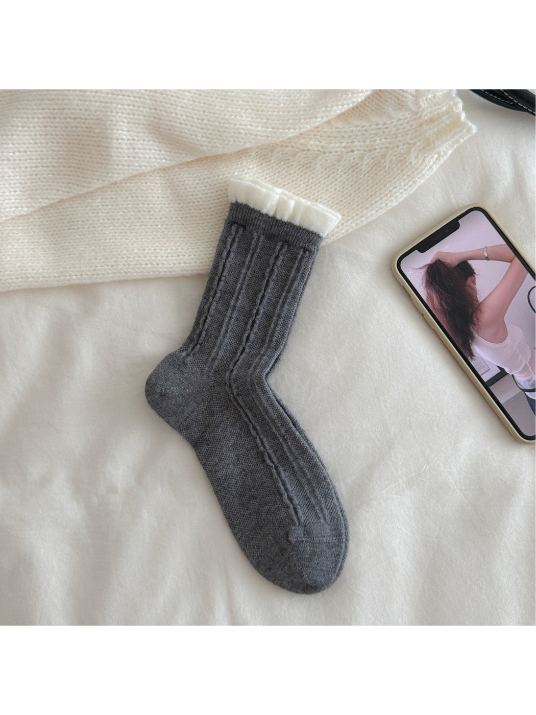 Dark gray cable-knit crew sock with contrasting white ruffled cuff, flat view