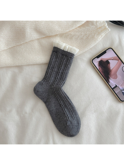 Dark gray cable-knit crew sock with contrasting white ruffled cuff, flat view