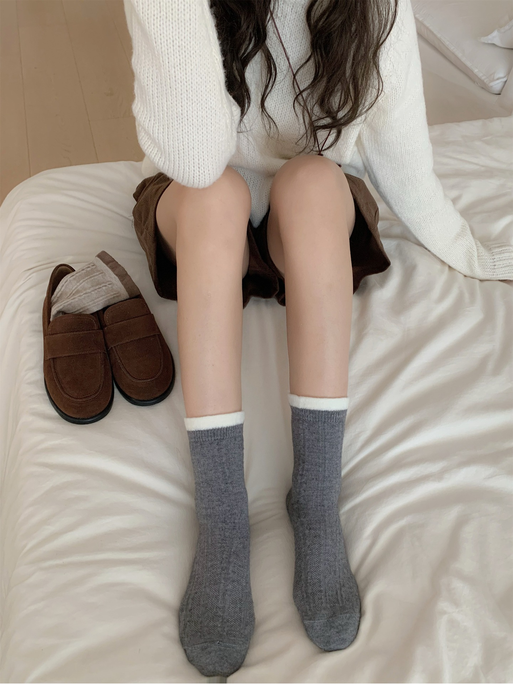 Pair of dark gray cable-knit crew socks worn with contrasting white cuffs