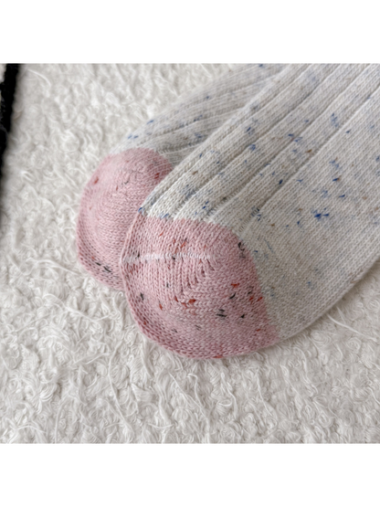 Close-up of rounded pink toe panels and speckled ribbed knit