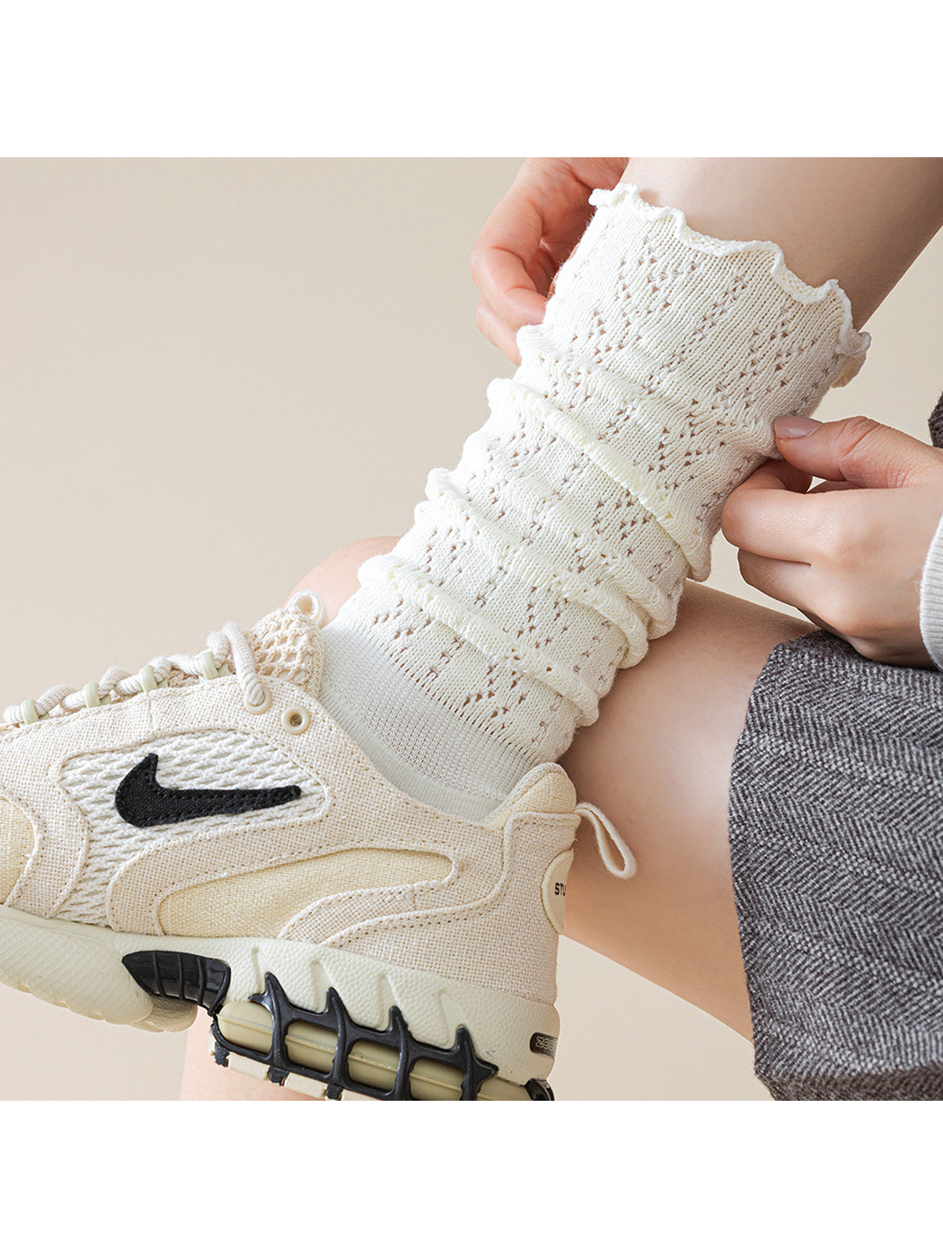 Close-up of an ivory sock with ruffled cuff and gathered pointelle texture