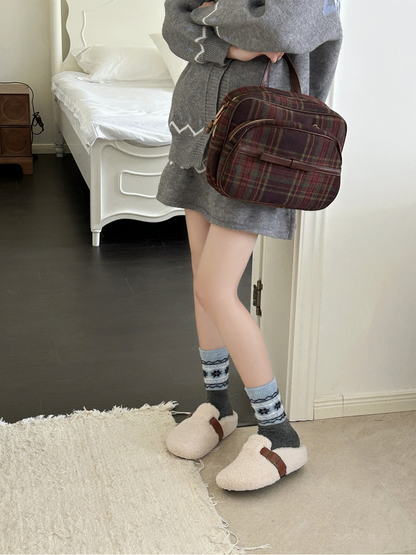 Dark gray snowflake crew socks worn with cream plush shoes