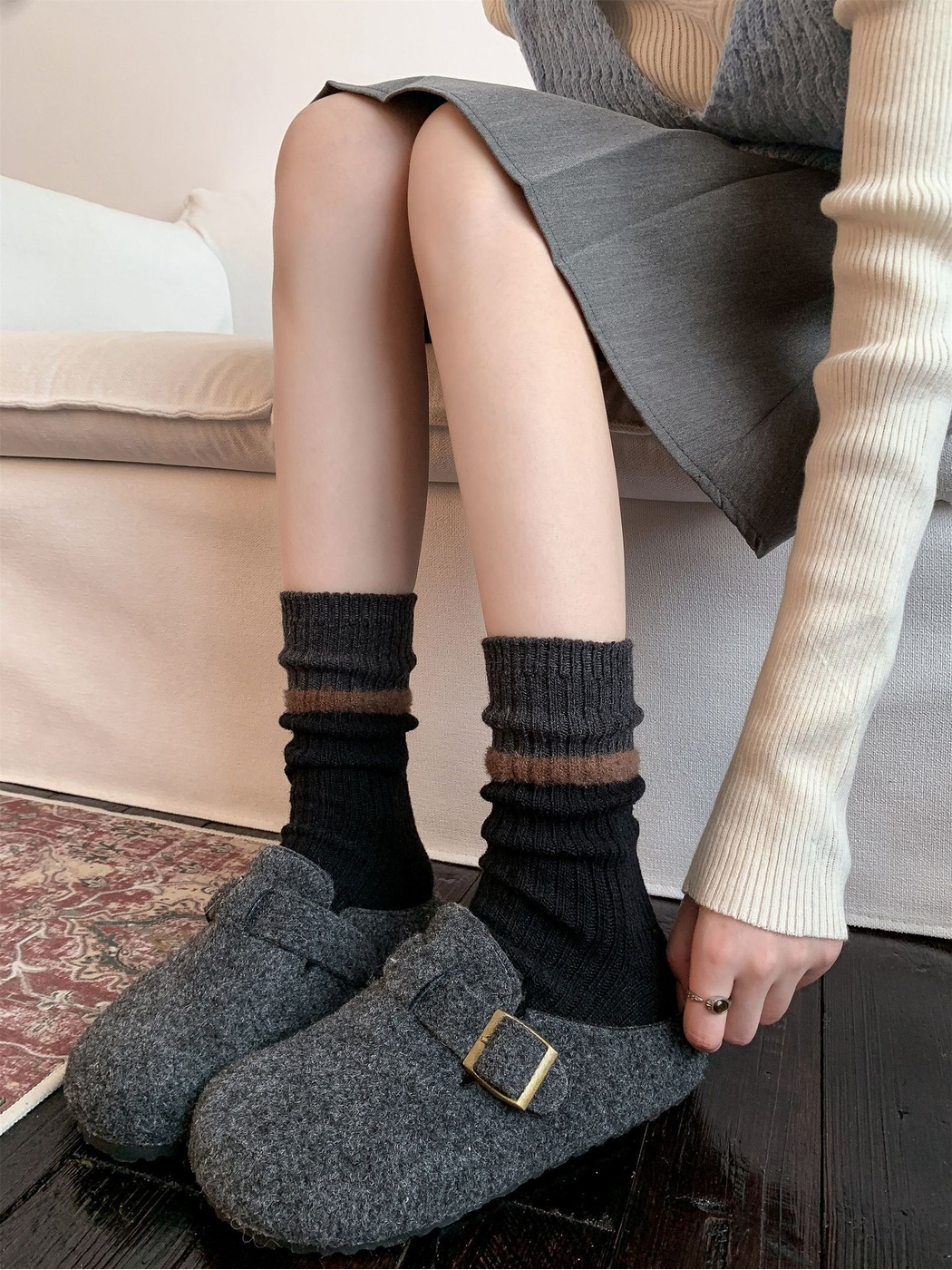 Black ribbed crew socks worn with gray buckle clogs