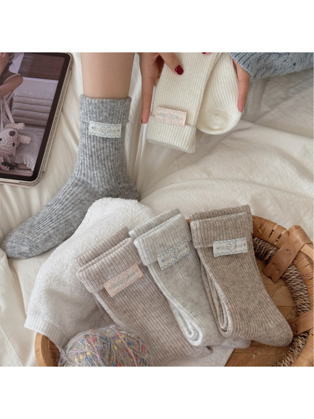 Neutral ribbed crew socks styled in a basket with one gray sock worn