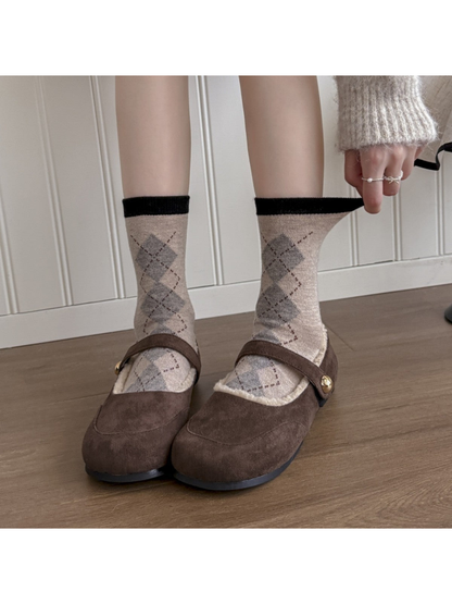 Beige argyle crew socks worn with brown shoes while the cuff is gently stretched