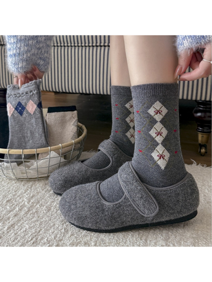 Dark gray crew socks with cream diamonds worn with gray slippers