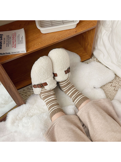 Khaki striped crew socks worn with cream slippers in a cozy indoor setting
