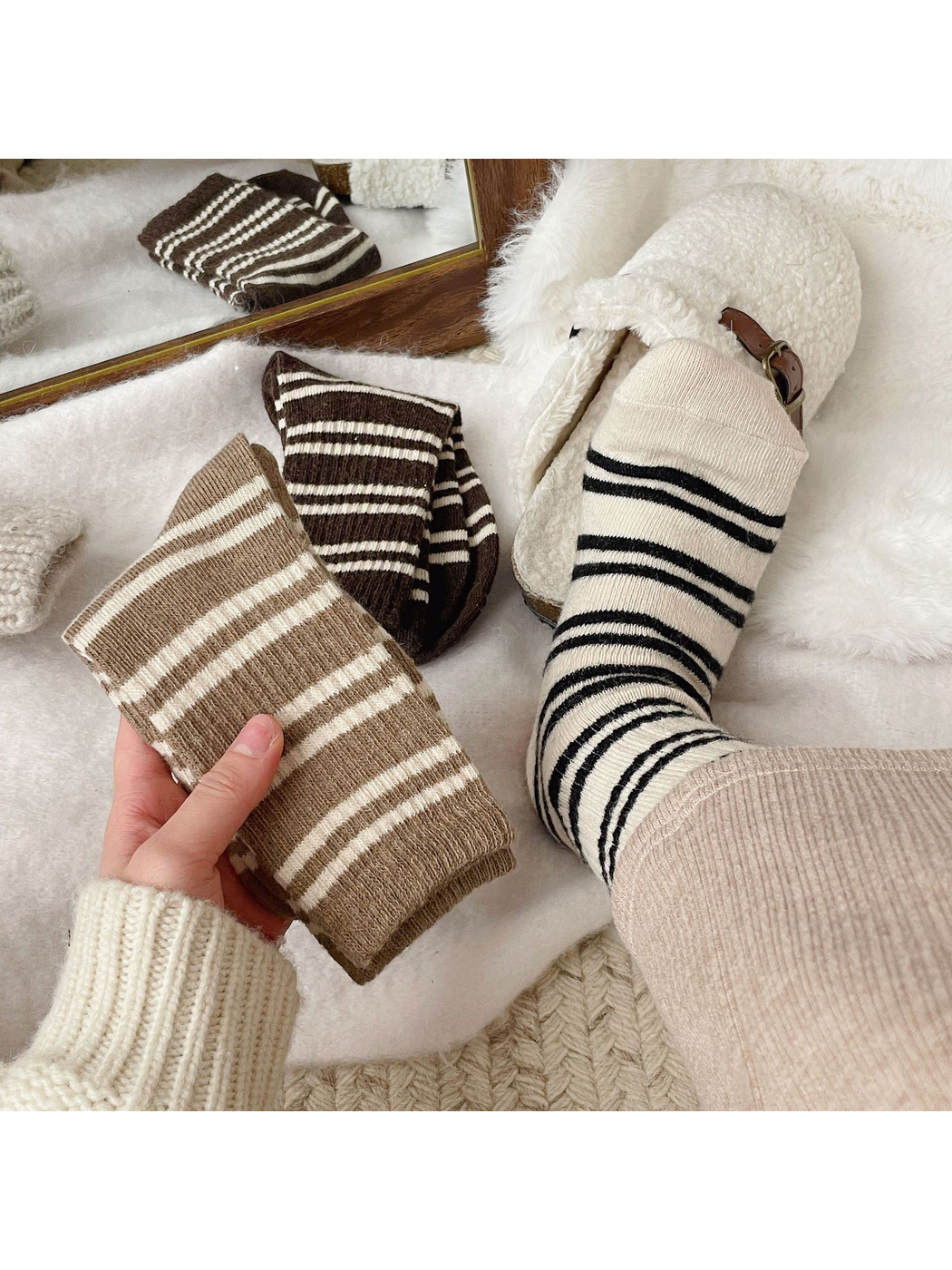 Khaki, dark brown and ivory striped crew socks styled beside cream slippers