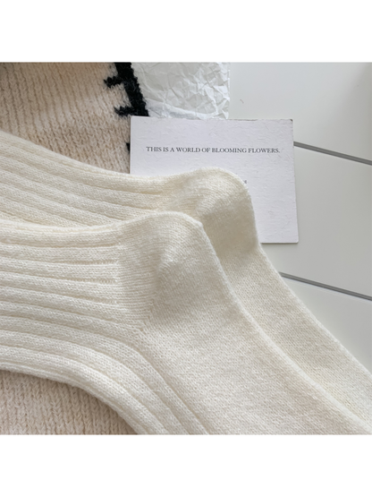 Close-up of shaped heels, rounded toes and vertical ribbing on ivory crew socks