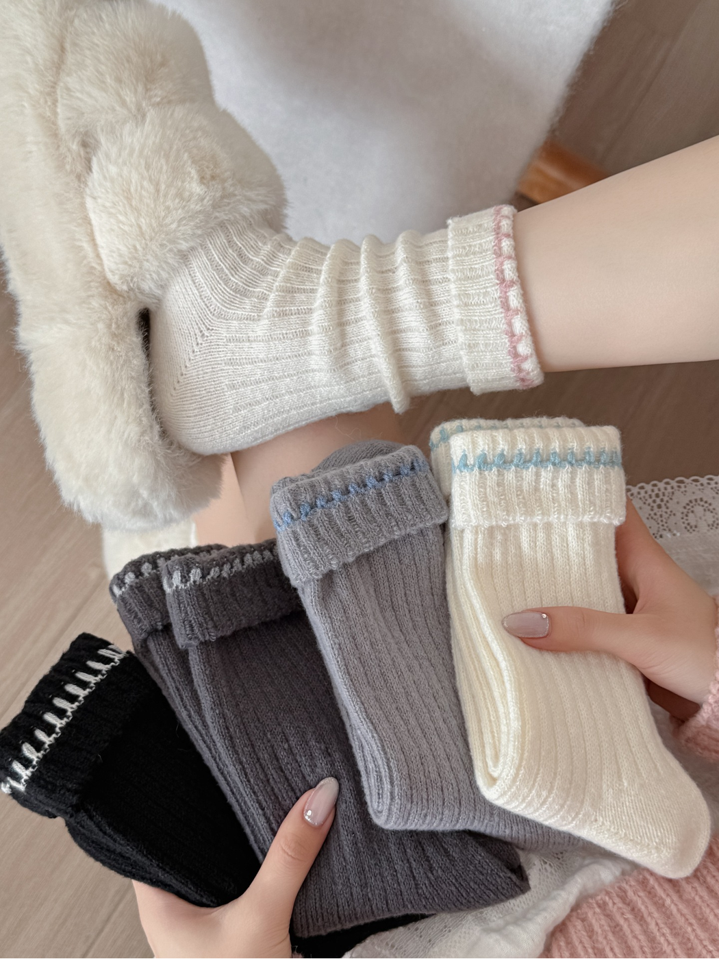 Pink-trimmed ivory sock worn with a plush slipper beside five folded colorways