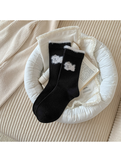 Black crew socks with a white fuzzy animal motif and cuff trim