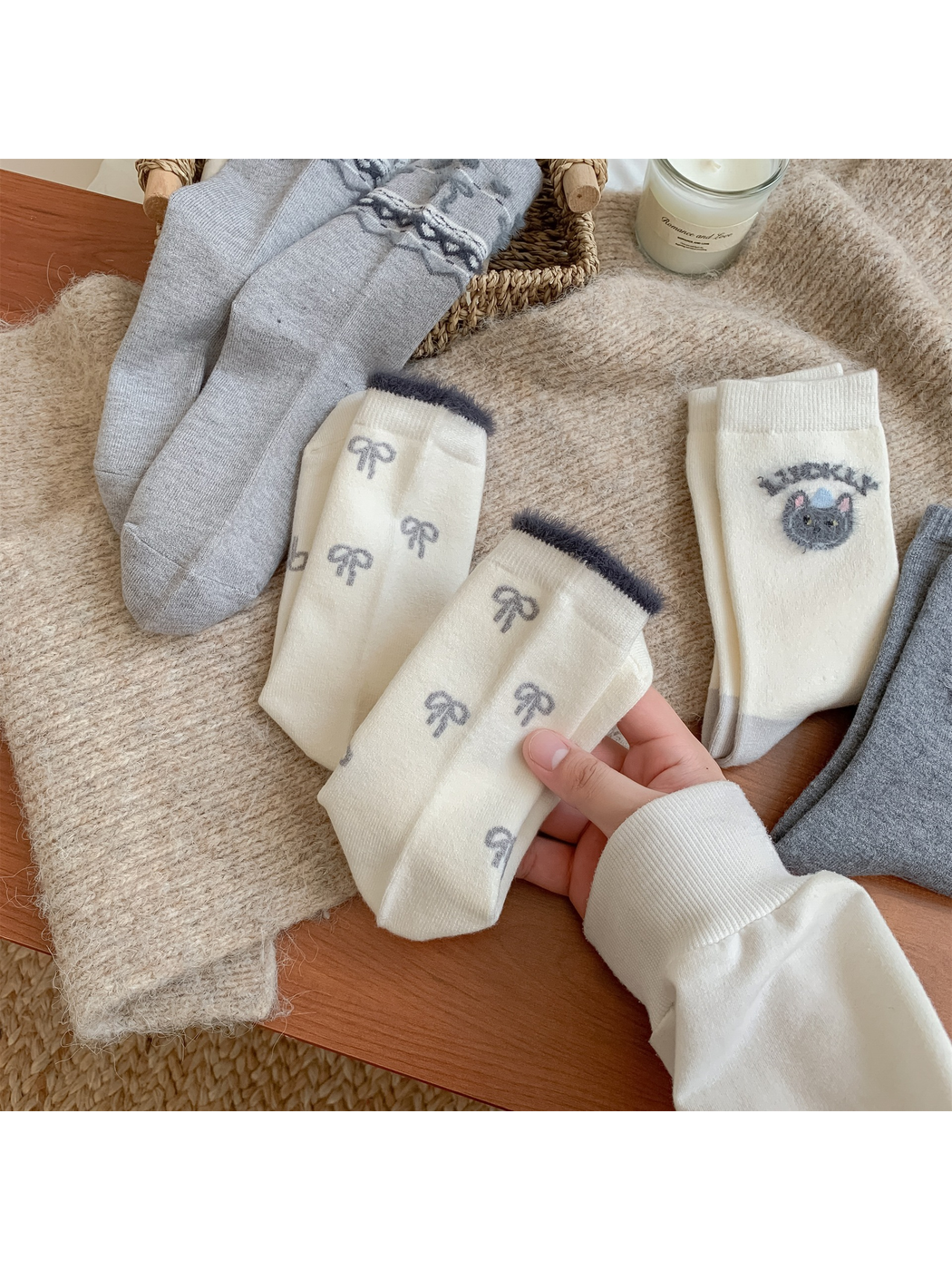 Hand holding ivory bow-pattern crew socks among coordinating designs