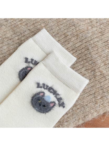 Close-up of fuzzy cat-face motifs below ribbed ivory cuffs
