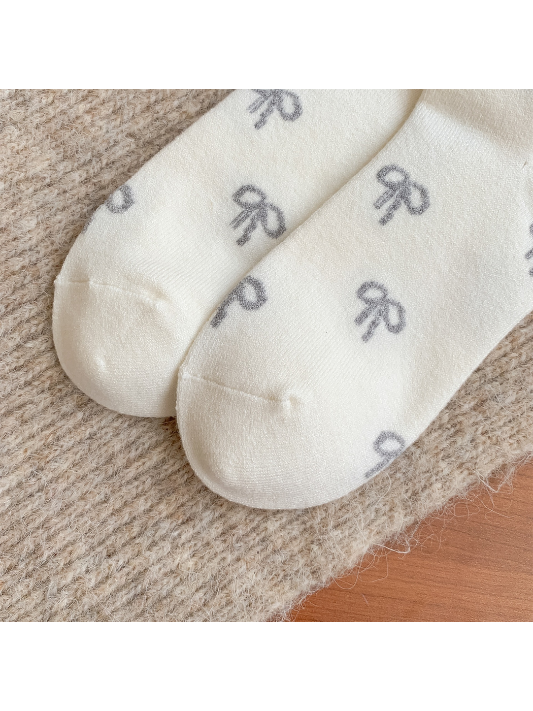 Close-up of rounded toe seams on ivory bow-pattern socks