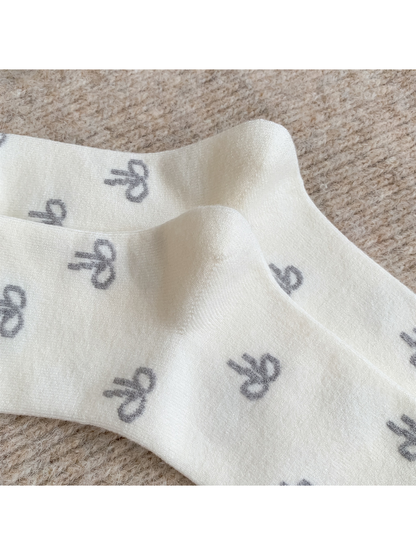 Close-up of the ivory knit texture and gray bow pattern