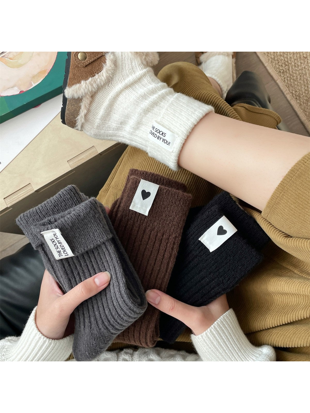 Cream socks worn with lined brown clogs beside folded gray, brown and black color options