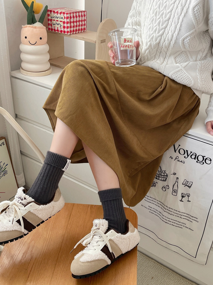 Dark gray ribbed crew socks styled with lined sneakers and a corduroy skirt